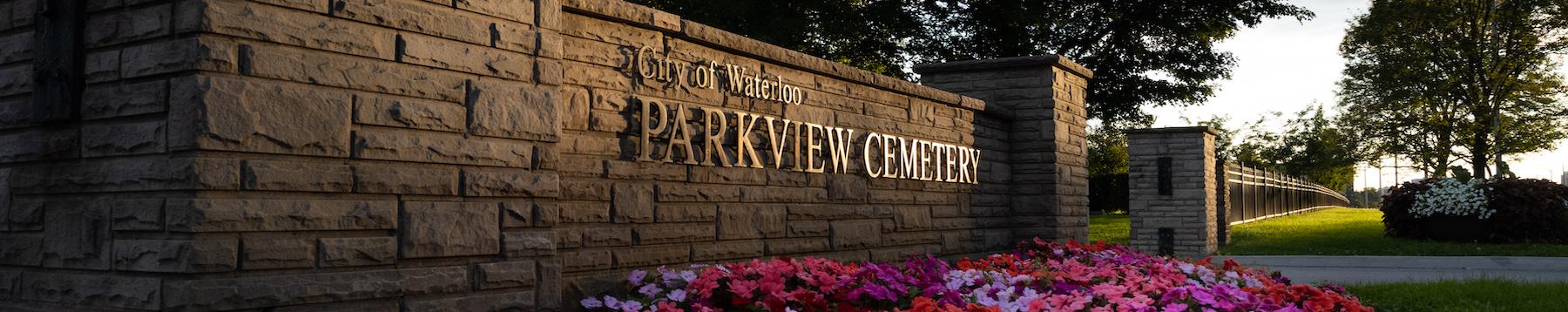 The front entrance of Parkview Cemetery with a sign on a brick wall