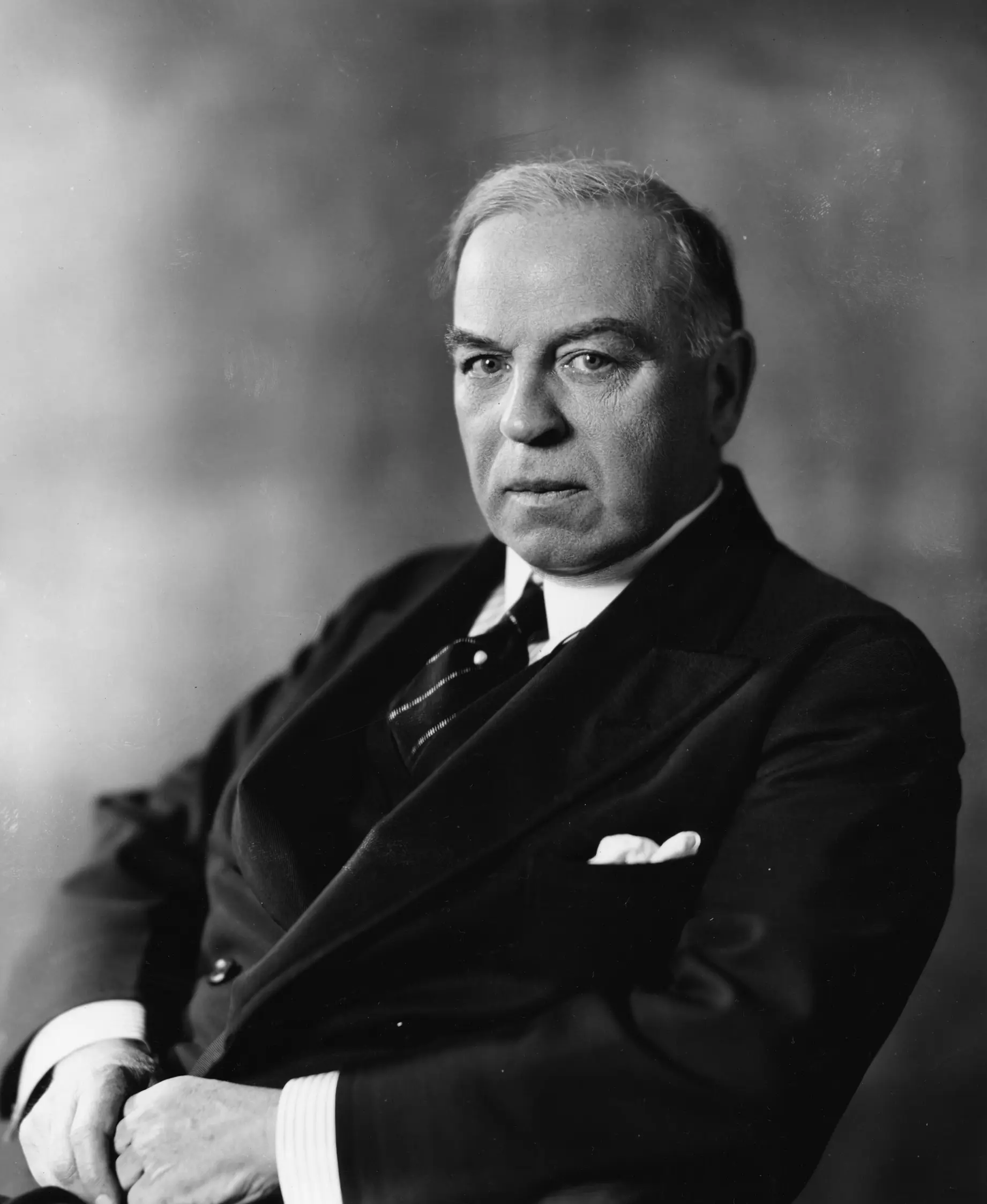 Image of man in dark suit sitting