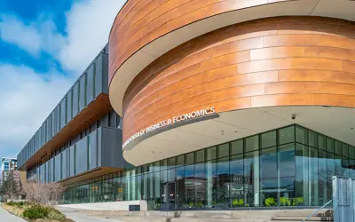 A modern Laurier building with dark panels and a large curved copper façade sits beside a busy street under a blue sky.