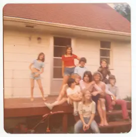 Image of 7 kids, 2 teens, and one adult on porch