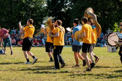 Marching band in yellow shirts performing on a field during the July 1 Community Picnic event.