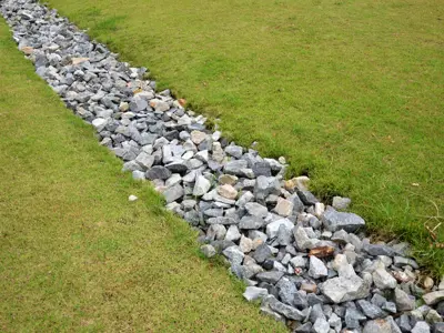 Illustration of an infiltration trench showing a gravel-filled pit beneath grass. The trench allows rainwater to soak into the ground instead of running off the surface.