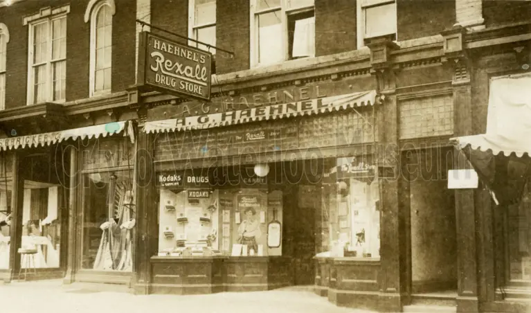 Image shows front of postcard with a black and white photo of the Haehnel Rexall Drug Store on King Street in Waterloo. 