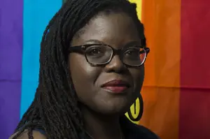 Portrait of Black woman in front of rainbow flag
