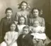 Black and white photo of 7 children sitting and standing