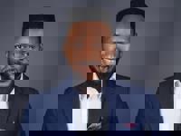 Headshot of a man in a suit with a dark grey background