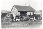 Black and white photo of Graybill and Shantz coal and wood dealers. Three men standing under business sign on right, two horse-drawn carts in the center and left.