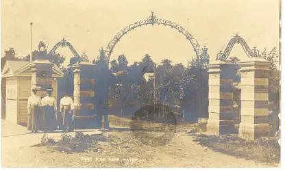 Archival image of the 1905 ornate iron and brick Young Street park entrance gate to Waterloo Park, flanked by limestone pillars and decorative lighting.