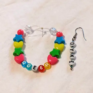 Image of beaded bracelet that reads "queer" and beaded earring that reads "dyke"
