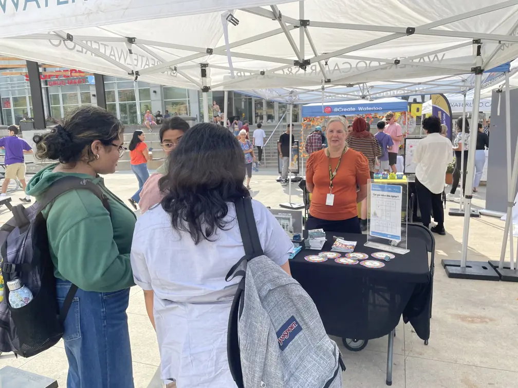 Museum volunteer at an outdoor event with a table showcasing current exhibits