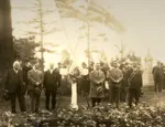 Brill (third from right) stands with five other men beside cross with wreath and two union jacks.