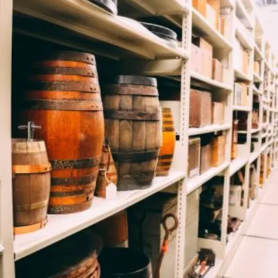 Image shows liquor barrels stacked high in a warehouse