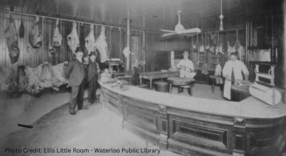 Image is a black and white photo of a butcher during Christmas time