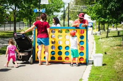 A group of people play a giant game of Connect 4 in Waterloo Park on a sunny day.