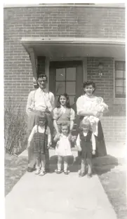 Image of family of 7 in front of home
