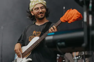 Guitar player performing on stage during an outdoor event.