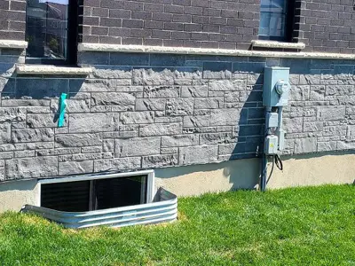 Diagram of a basement window with a surrounding window well, showing drainage, gravel, and how water is kept out of the window area.